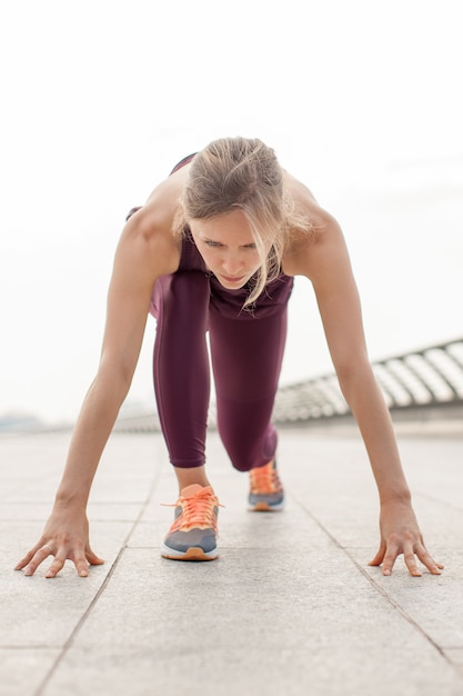 Jeune femme motivée en position de départ sur le pont