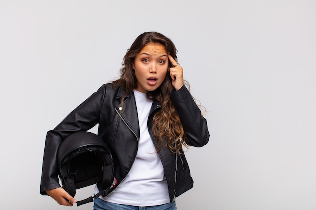 Jeune femme motocycliste à la surprise, bouche bée, choqué, réalisant une nouvelle pensée, idée ou concept