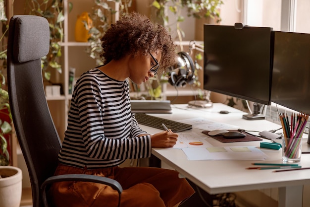 Jeune femme multiraciale étudiant des documents à la maison