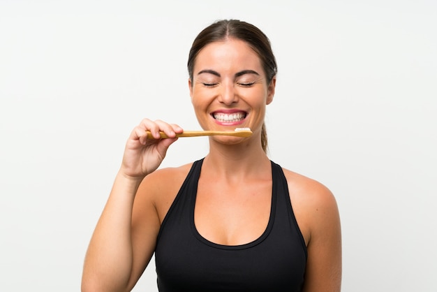 Jeune femme sur un mur blanc isolé se brosser les dents