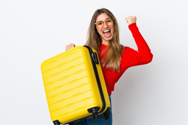 Jeune femme sur un mur blanc isolé en vacances avec valise de voyage