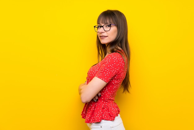 Jeune femme sur un mur jaune avec les bras croisés et avec impatience