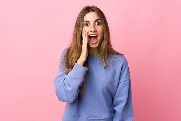 Jeune femme sur un mur rose isolé avec surprise et expression faciale choquée