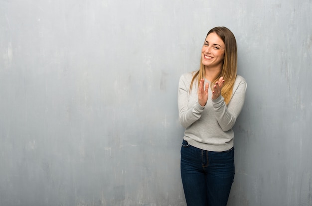 Jeune femme sur un mur texturé applaudissant après une conférence