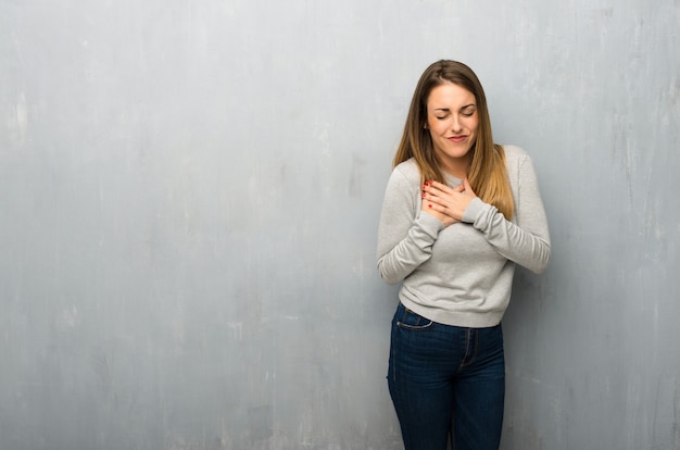 Jeune femme sur un mur texturé ayant une douleur au coeur