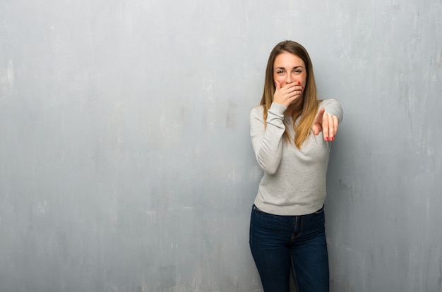 Jeune femme, mur texturé, pointer, doigt, quelqu&#39;un, rire