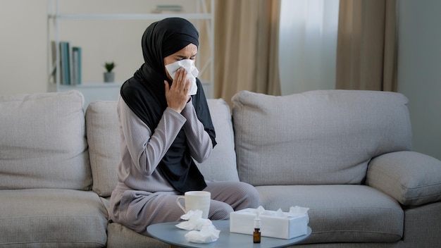 Une jeune femme musulmane arabe malade en hijab souffre de la maladie de la grippe nasale qui coule saisonnière