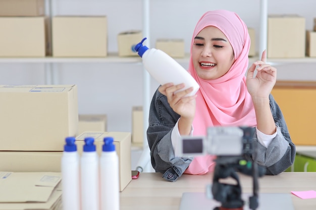 Jeune femme musulmane asiatique active blogger ou vlogger en veste en jean regarde la caméra et parle en tournage vidéo