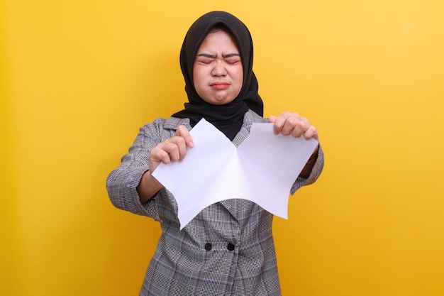 Jeune femme musulmane asiatique adulte déchirant du papier avec une expression triste et déçue