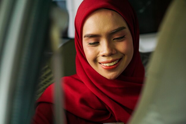 Jeune femme musulmane asiatique en hijab à l'aide d'un smartphone souriant en voiture