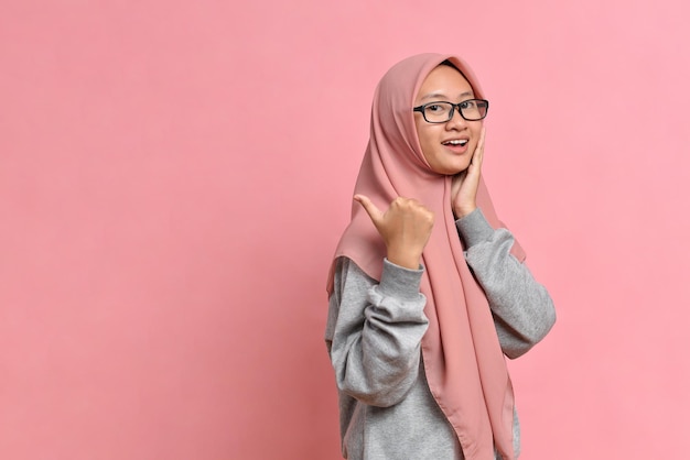 Jeune femme musulmane asiatique montrant le pouce vers le haut sur fond de couleur rose. Maquette de l'espace de copie. Montrant le pouce vers le haut.