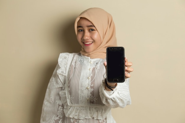 Jeune femme musulmane asiatique portant le hijab montrant un téléphone mobile à écran blanc