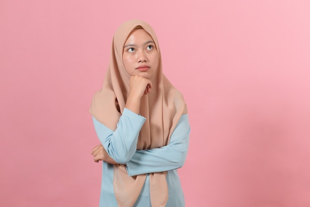 Jeune femme musulmane asiatique regardant un espace de copie ou pensant à une idée ; isolé sur fond rose