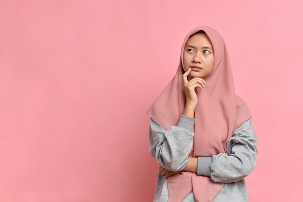 Jeune femme musulmane asiatique regardant un espace de copie ou pensant à une idée ; isolé sur fond rose