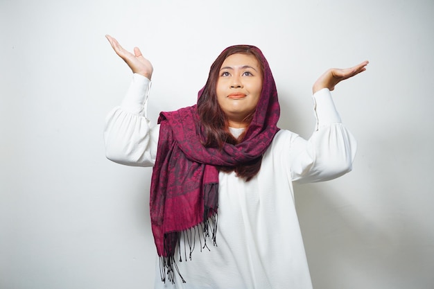 Photo jeune femme musulmane asiatique souriante tout en pointant pour copier l'espace à côté d'elle