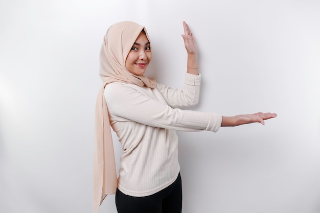 Jeune femme musulmane asiatique souriante tout en pointant pour copier l'espace à côté d'elle