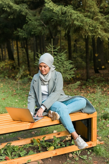 Jeune femme musulmane asiatique utilisant un ordinateur portable au parc d'automne éducation en ligne achats en ligne et social