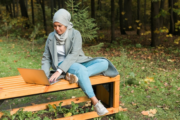 Jeune femme musulmane asiatique utilisant un ordinateur portable au parc d'automne éducation en ligne achats en ligne et social