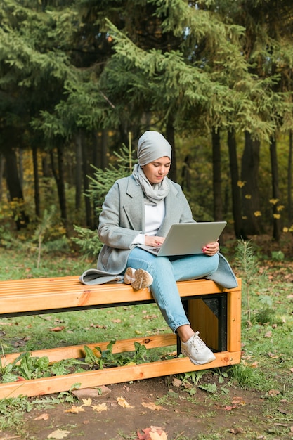 Jeune femme musulmane asiatique utilisant un ordinateur portable au parc d'automne éducation en ligne achats en ligne et social