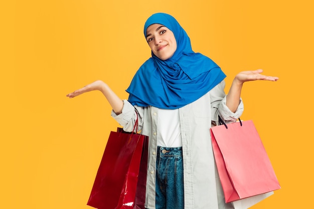 Jeune femme musulmane avec des emballages colorés sur jaune.