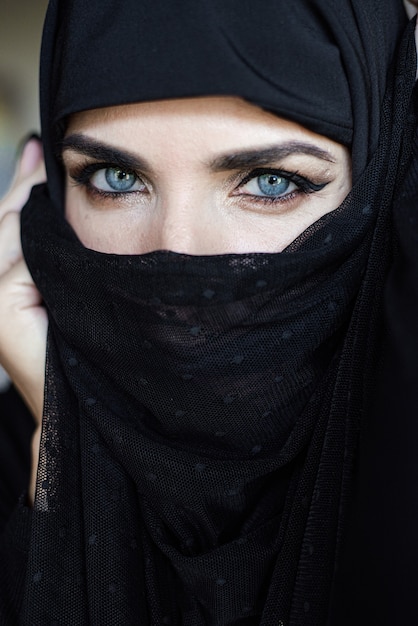 Jeune femme musulmane sur fond sombre portant un hijab noir