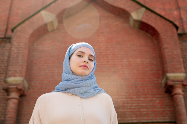 Jeune femme musulmane en hijab debout du mur du palais oriental