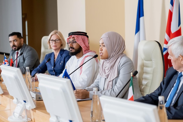 Jeune femme musulmane en hijab faisant un rapport à des collègues étrangers