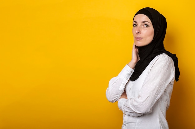 Jeune femme musulmane en hijab souriant sur un jaune