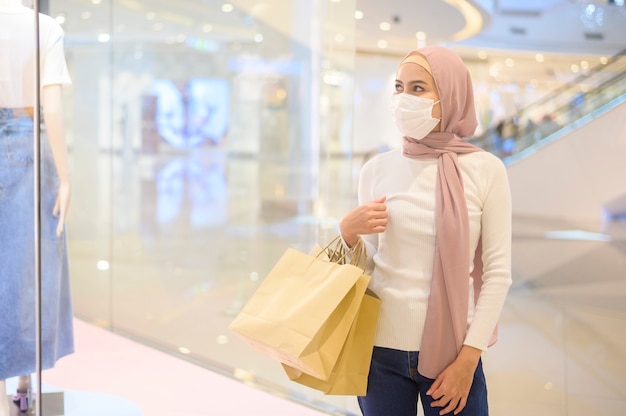 Une jeune femme musulmane portant un masque de protection dans un centre commercial