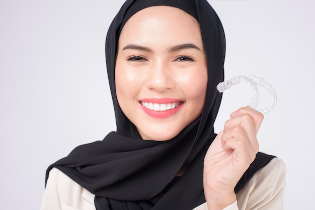 Jeune Femme Musulmane Tenant Des Accolades Invisalign En Studio, Soins Dentaires Et Concept Orthodontique.