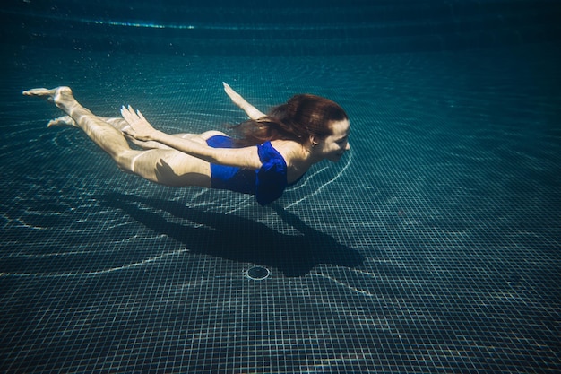 Jeune femme nageant sous l'eau dans la piscine