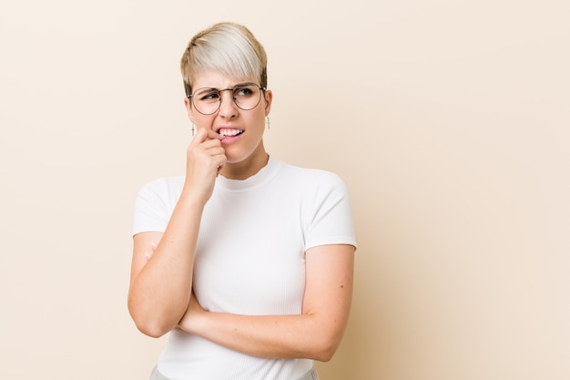 Jeune femme naturelle authentique portant une chemise blanche détendue en pensant à quelque chose en regardant un espace de copie.