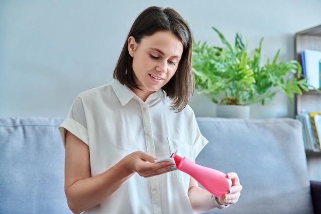 Jeune femme nettoie son visage avec des tampons de coton à l'aide d'un tonique cosmétique