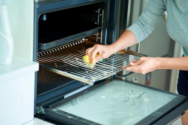 Jeune femme nettoyant le four dans la cuisine