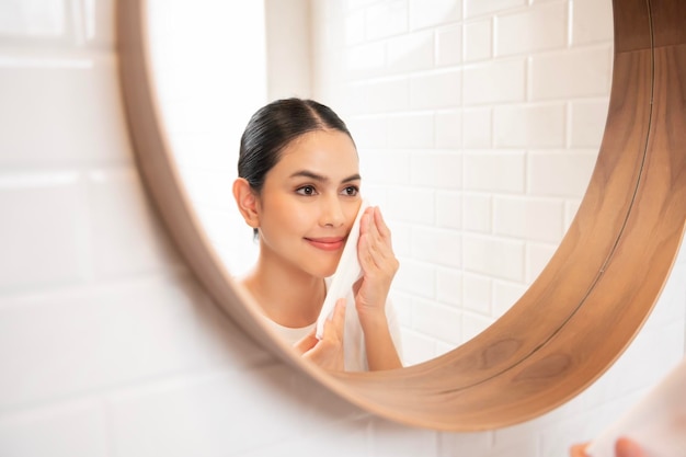 Jeune femme nettoyant le maquillage sur son visage dans la salle de bain à la maison concept de bien-être beauté