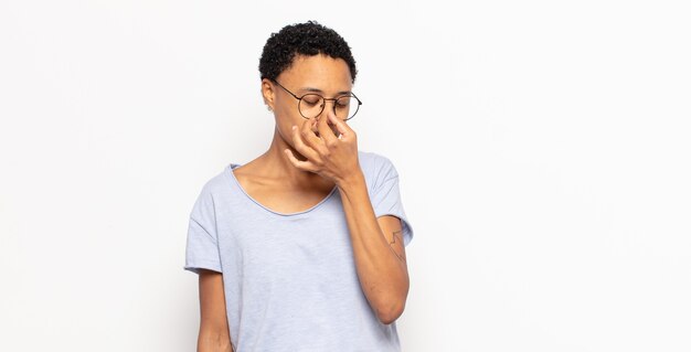 Jeune femme noire afro se sentant stressée, malheureuse et frustrée, touchant le front et souffrant de migraine de maux de tête sévères