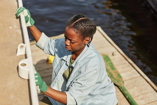 Jeune femme noire à angle élevé nettoyant un bateau à quai