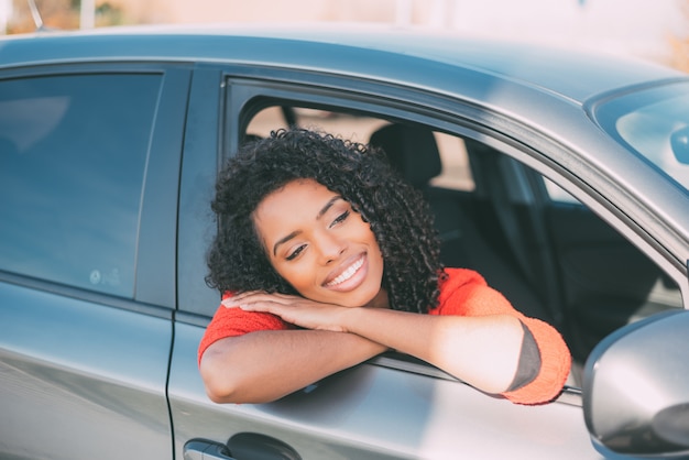 Jeune femme noire assise dans la voiture en souriant