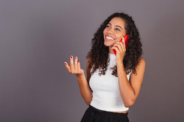 Jeune femme noire brésilienne parlant sur appel vocal avec un téléphone portable rouge