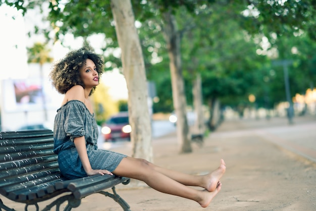 Jeune femme noire avec une coiffure afro souriant en contexte urbain