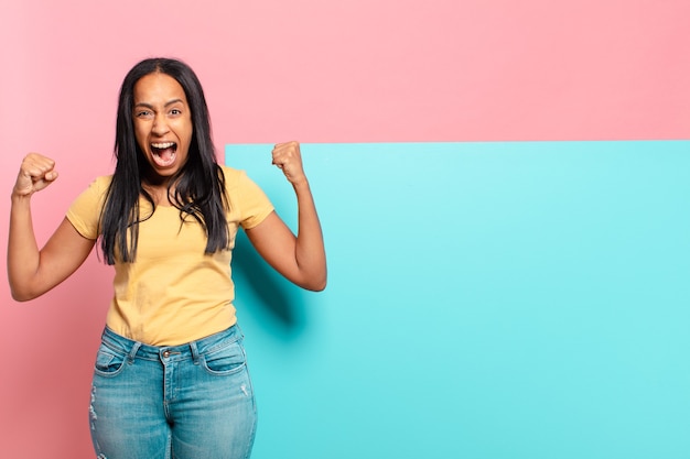 Jeune femme noire criant de manière agressive avec une expression de colère ou les poings serrés pour célébrer le succès. copie concept d & # 39; espace