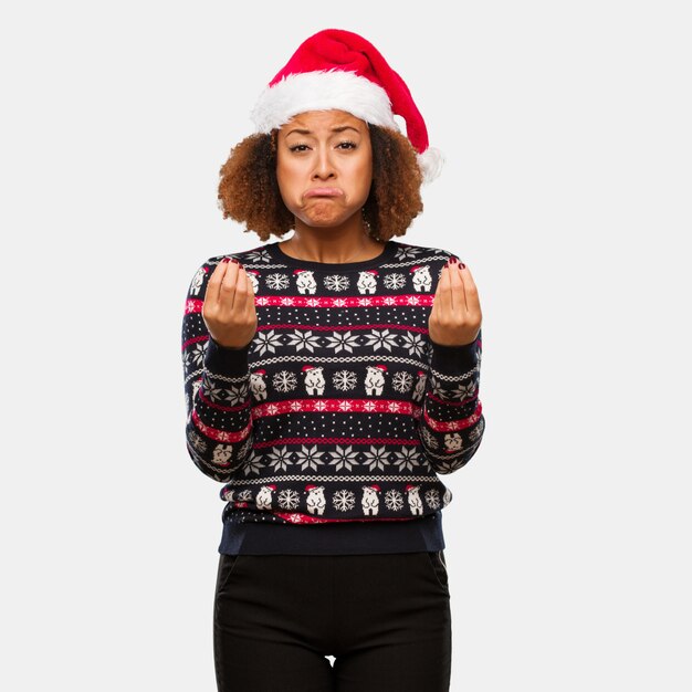 Jeune femme noire dans un pull de Noël à la mode avec une impression faisant un geste de nécessité