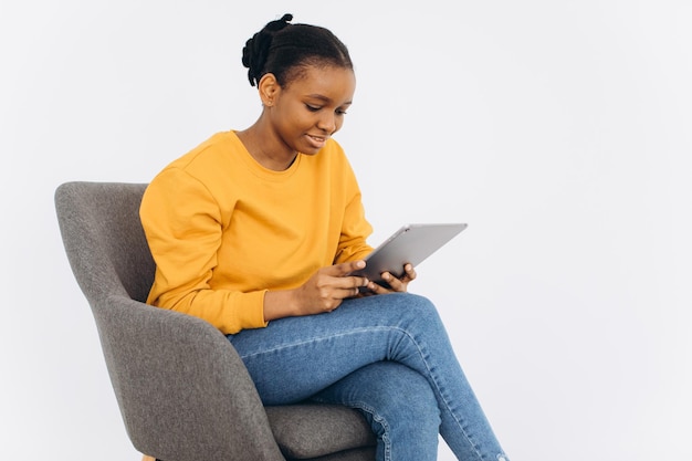 Jeune femme noire dans une veste jaune regarde la tablette