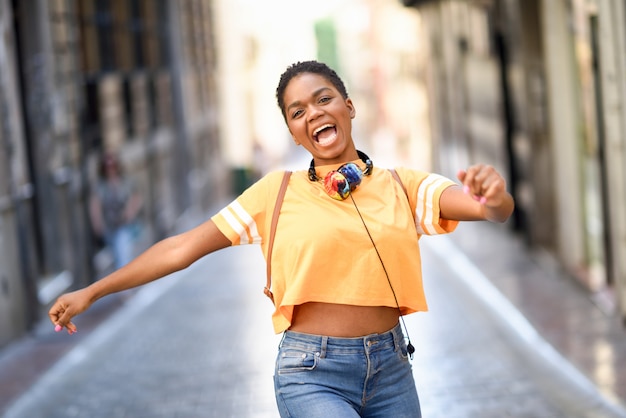 Jeune femme noire danse dans la rue en été.