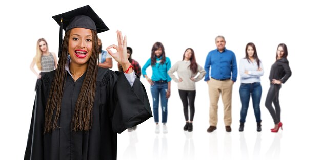 Photo jeune femme noire diplômée portant des tresses gaies et confiantes faisant un geste ok, excité et hurlant, concept d'approbation et de réussite