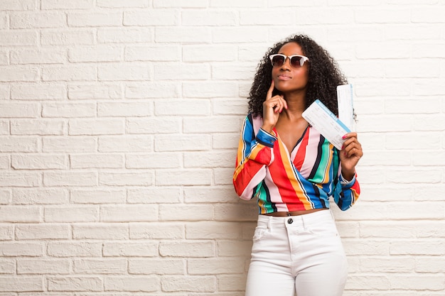 Photo jeune femme noire douteuse et confuse, pensant à une idée ou inquiète de quelque chose