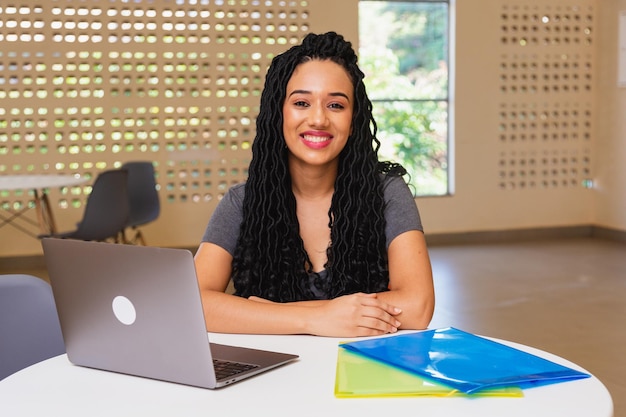 Jeune femme noire étudiante à l'université brésilienne travaillant sur ordinateur portable souriant à la caméra