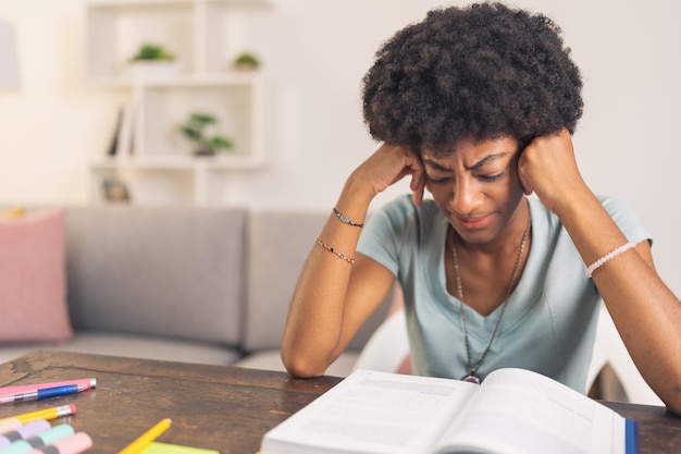 Jeune femme noire fatiguée lisant un livre