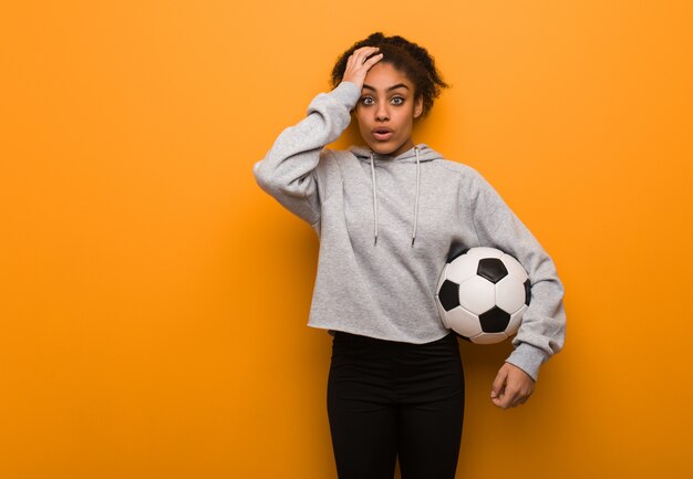 Jeune femme noire fatiguée et très fatiguée. Tenir un ballon de foot.