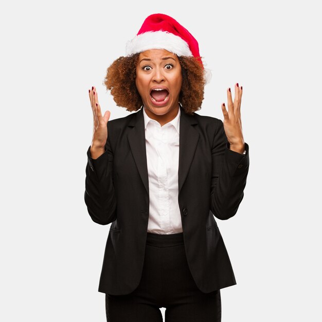 Jeune femme noire portant un bonnet de Noel chirstmas célébrant une victoire ou un succès